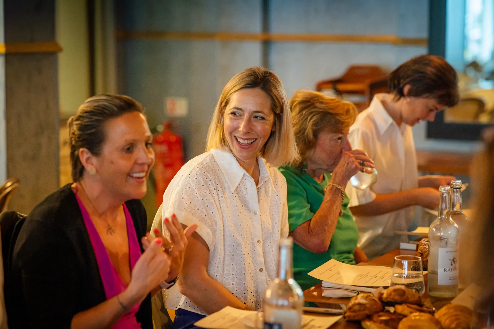 Women clapping and smiling at an EmpowerHER breakfast